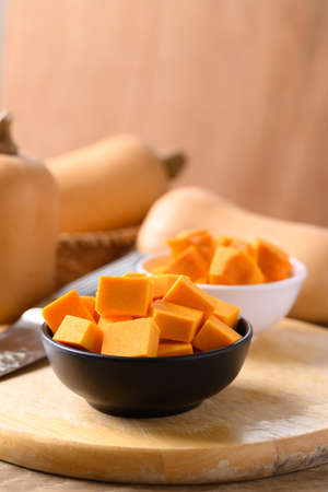 Sliced butternut squash in a bowl on wooden board preparing for cookingの写真素材