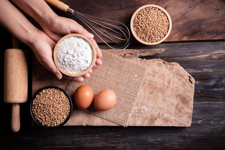 Kitchen utensil for bakery cooking and food ingredients (wheat grain, flour and egg) on wooden background, Table top viewの写真素材