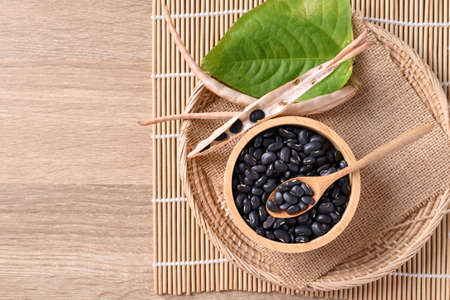 Black kidney beans in a bowl with spoon on wooden background, Table top viewの写真素材