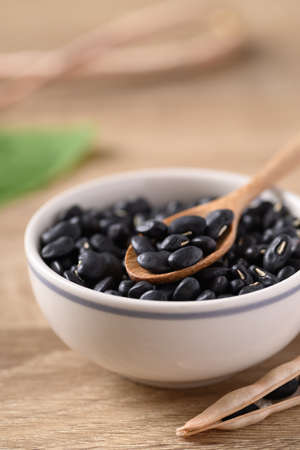 Black kidney beans in a bowl with spoon on wooden backgroundの写真素材
