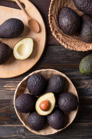Ripe hass avocado fruit in a basket on wooden background, Healthy eating, Table top view