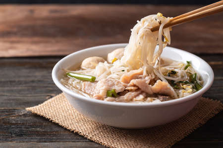 Rice noodles soup with pork and pork ball in a bowl on wooden background, Thai noodles soup