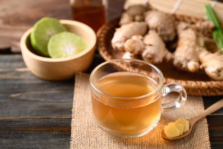 Ginger tea with lime and honey on wooden background, Healthy herbal drink