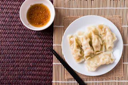 Steamed wonton dumpling stuffed with minced pork on plate eating with sesame oil sauce, Asian food, Top viewの写真素材