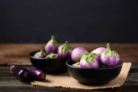 Fresh organic Thai purple eggplant in bowl on wooden background, Food ingredient