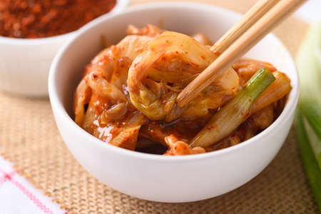Kimchi cabbage in a bowl eating by use chopsticks, Korean homemade fermented side dish foodの写真素材