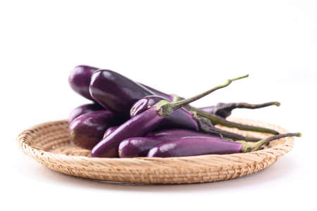 Fresh organic purple eggplant in small basket on white background, Food ingredientの写真素材
