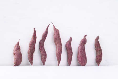 Organic purple sweet potatoes on white background, Ugly vegetable concept, food trendの写真素材