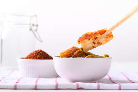 Kimchi cabbage in a bowl eating by use chopsticks on white background, Korean homemade fermented side dish foodの写真素材