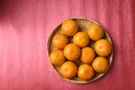 Orange fruit in bamboo basket on red background, Chinese New Year, Lunar New Yearの写真素材