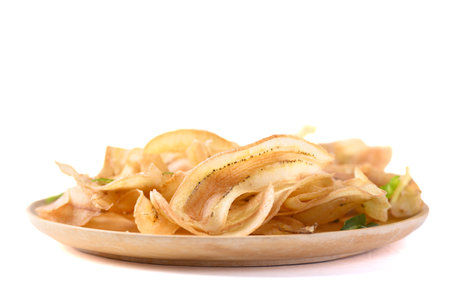 Banana chips or banana crisps on wooden plate with white background, Delicious snackの写真素材