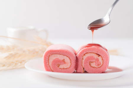 Pink strawberry roll cake or swiss roll with whipped cream and strawberry flavor eating with...