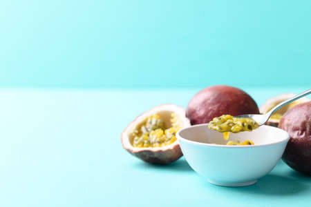 Passion fruit juice in bowl with spoon for eating on pastel color background, Tropical fruit in...