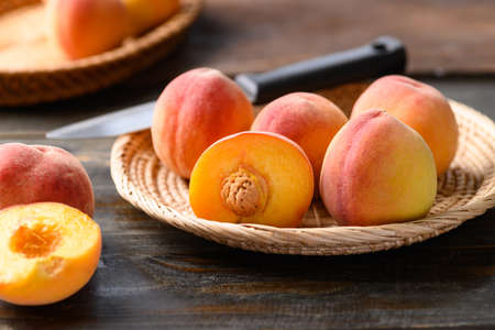 Peach fruit in basket on wooden backgroundの写真素材