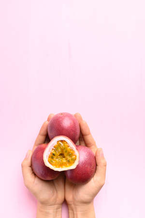 Fresh passion fruit holding by hand on pink background, Tropical fruit in summer season