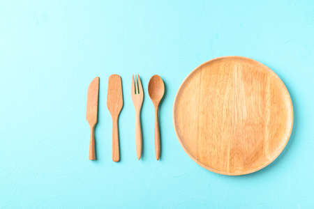 Kitchen utensil (wooden plate, fork and spoon) on color backgroundの写真素材