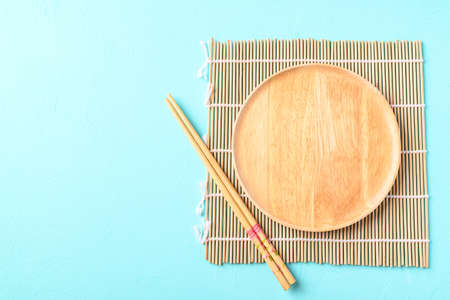 Kitchen utensil (wooden plate and chopsticks) on color backgroundの写真素材