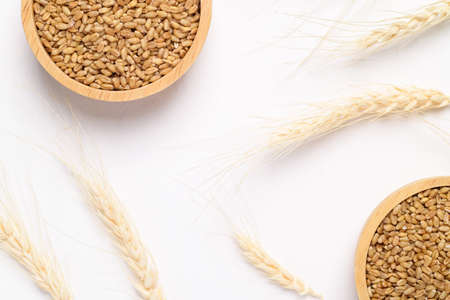 Whole wheat grain in wooden bowl on white background, food ingredients, Top viewの写真素材
