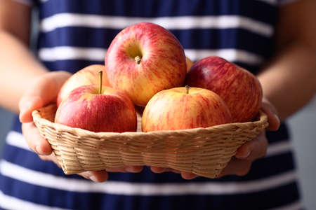 Red apple fruit in basket holding by woman hand, Healthy fruit
