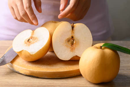 Asian pear or Nashi pear with hand on cutting wooden boardの写真素材