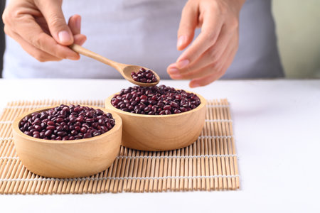 Azuki beans, Adzuki bean or red mung beans in wooden bowl with hand, Food ingredients in many Chinese dishes and filling in Japanese sweetの写真素材