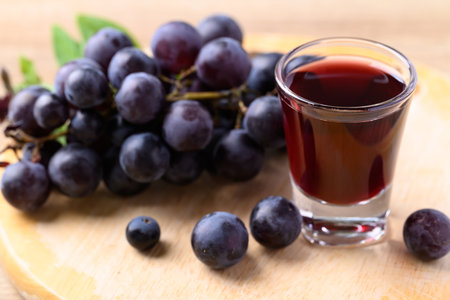 Black grape and juice in glass on wooden board, healthy drinkの写真素材