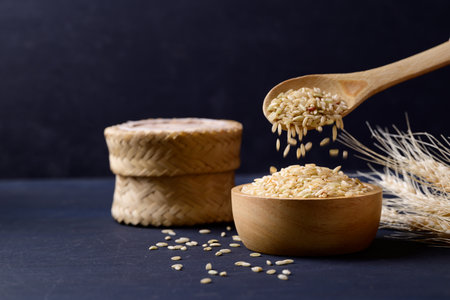 Organic Thai brown rice grain in wooden bowl on black background, Asian healthy food ingredientsの写真素材