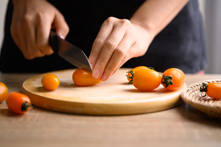 Orange cherry tomato cutting on wooden board, fresh organic vegetableの写真素材