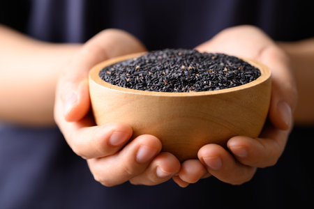 Black sesame seed in bowl holding by handの写真素材