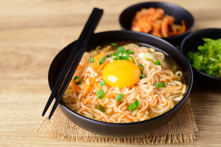 Asian instant noodle soup with fresh egg yolk eating with kimchi cabbage and seaweed saladの写真素材