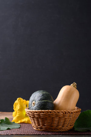 Green pumpkin and butternut squash in basket on wooden table with black background, Organic vegetable in Autumn seasonの写真素材