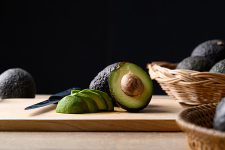 Ripe hass avocado fruit on wooden board with black background, Healthy fruit