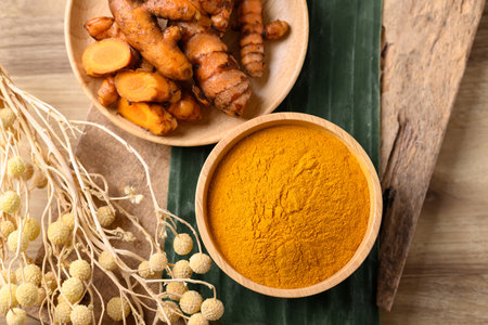 Turmeric powder and fresh turmeric in wooden bowl, Spice in Asian cuisine, Table top viewの写真素材