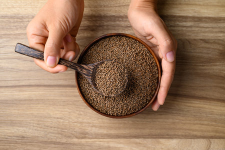 Perilla seed in bowl with spoon holding by hand on wooden background, Healthy herbal seed ingredients in Asian food, Table top viewの写真素材