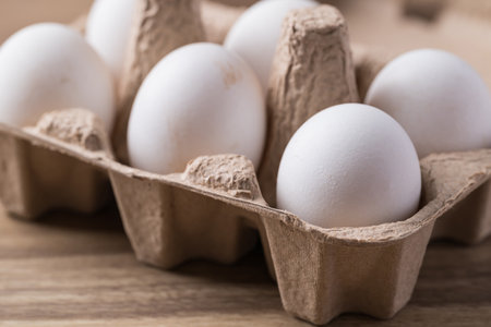 Organic white leghorn egg from free range farm in paper tray on wooden table