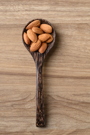 Raw almond in spoon on wooden background, Table top viewの写真素材