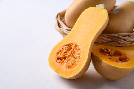 Half butternut squash pumpkin in basket on white backgroundの写真素材