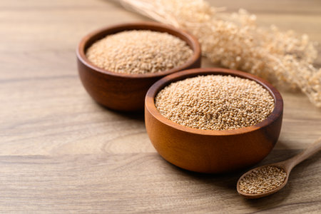 Brown quinoa seed in bowl with spoon on wooden background, Healthy food ingredientの写真素材