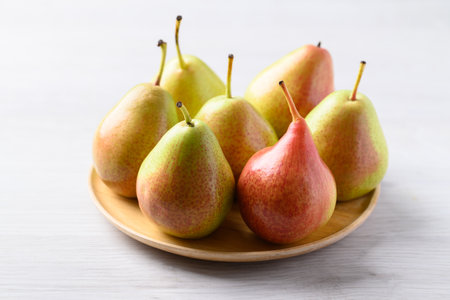 Fresh pear fruit on wooden plate with white table