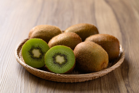 Green kiwi fruit in basket on wooden background, Tropical fruitの写真素材