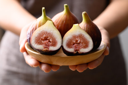 Fresh fig on wooden plate holding by hand, Healthy fruitの写真素材