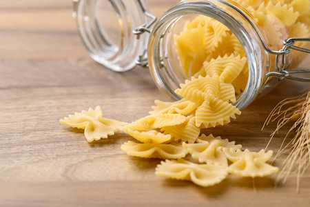 Uncooked farfalle pasta (bow tie shape) in glass jar, Italian food ingredientの写真素材