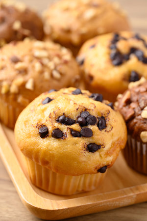 Vanilla chocolate chips muffin and chocolate almond muffin on wooden plateの写真素材