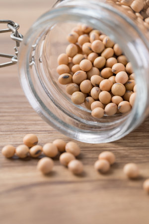 Soy bean seeds in glass jar on wooden backgroundの写真素材