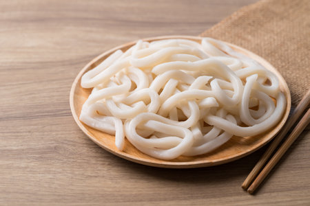 Udon noodles on wooden plate with chopsticks, Thick noodles in Japanese cuisineの写真素材