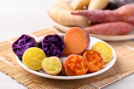 Steamed purple, orange and yellow sweet potatoes on plate ready to eatingの写真素材