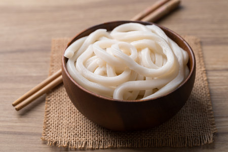 Udon noodles in wooden bowl with chopsticks, Thick noodles in Japanese cuisineの写真素材
