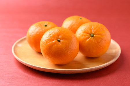 Mandarin tangerine orange fruit on wooden plate with red background, Lucky food in Lunar New Year or Chinese New Yearの写真素材