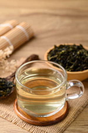 Hot green tea in cup glass and dried tea leaves in bowl with spoon on wooden background, Healthy drinkの写真素材