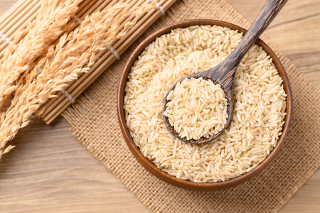 Organic Jasmine brown rice seed in wooden bowl with spoon, Thai Rice, Table top viewの写真素材